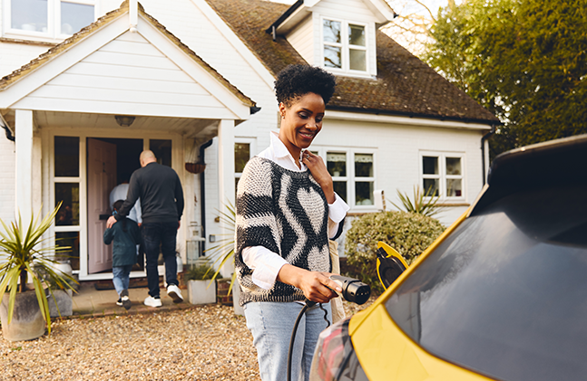 woman plugging in a charger for her electric car