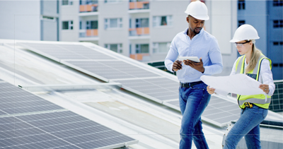 Two professionals on a commercial roof with solar panels